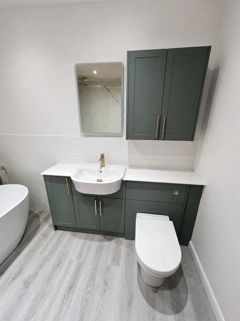Sage-green fitted vanity unit with brushed-brass tap