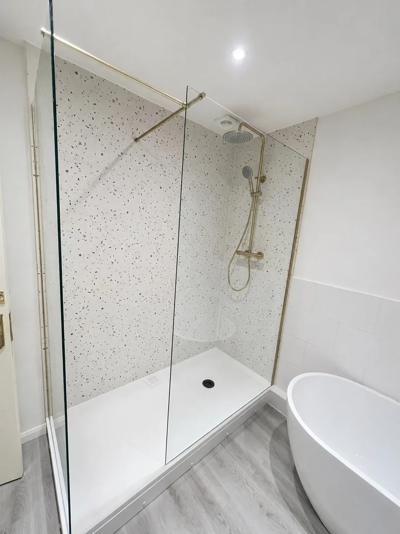 Walk-in terrazzo shower enclosure with brushed-brass fittings
