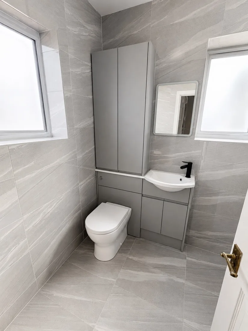 Completed grey-tiled bathroom with fitted vanity unit, basin and WC