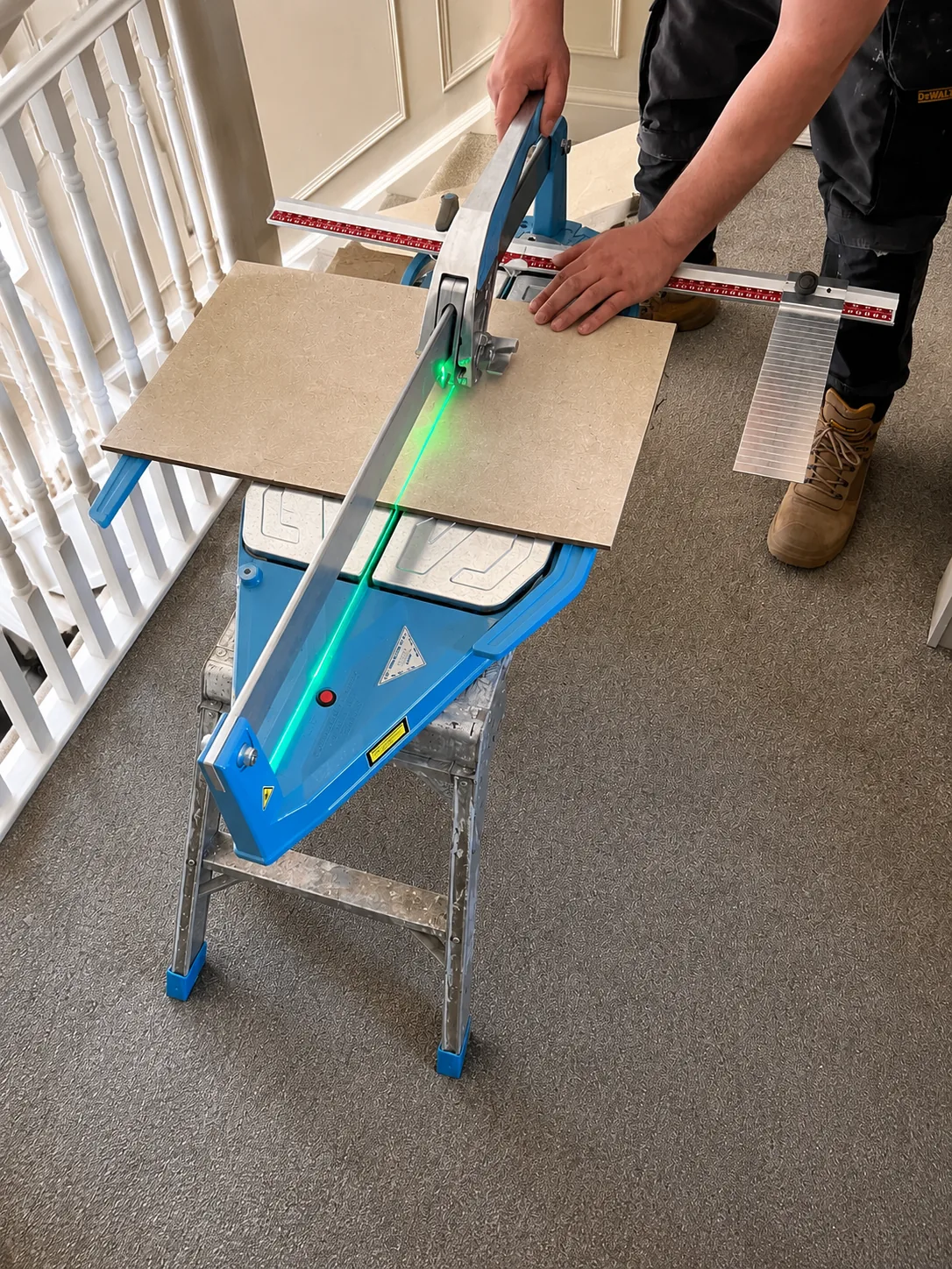 A Barrington Interiors fitter scoring a large-format tile on a manual cutter